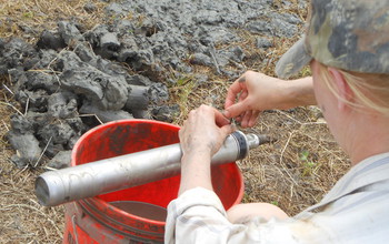 A scientist extracting a riverbank sample from a sampling device.